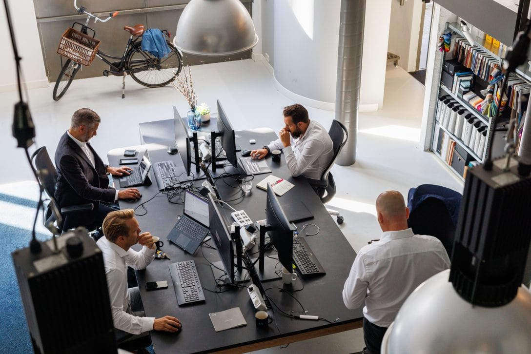 Staff working at a bank of desks inside the AIS Amsterdam studio.