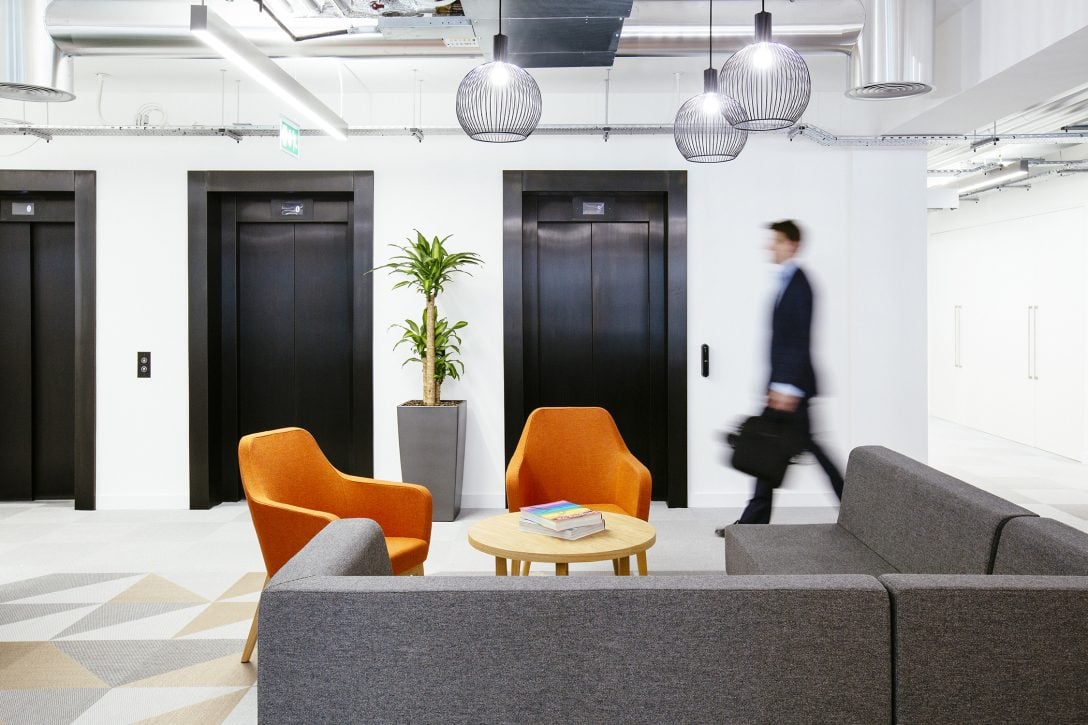 A man is shown walking towards a lift inside the offices of Versus Arthritis designed by AIS.