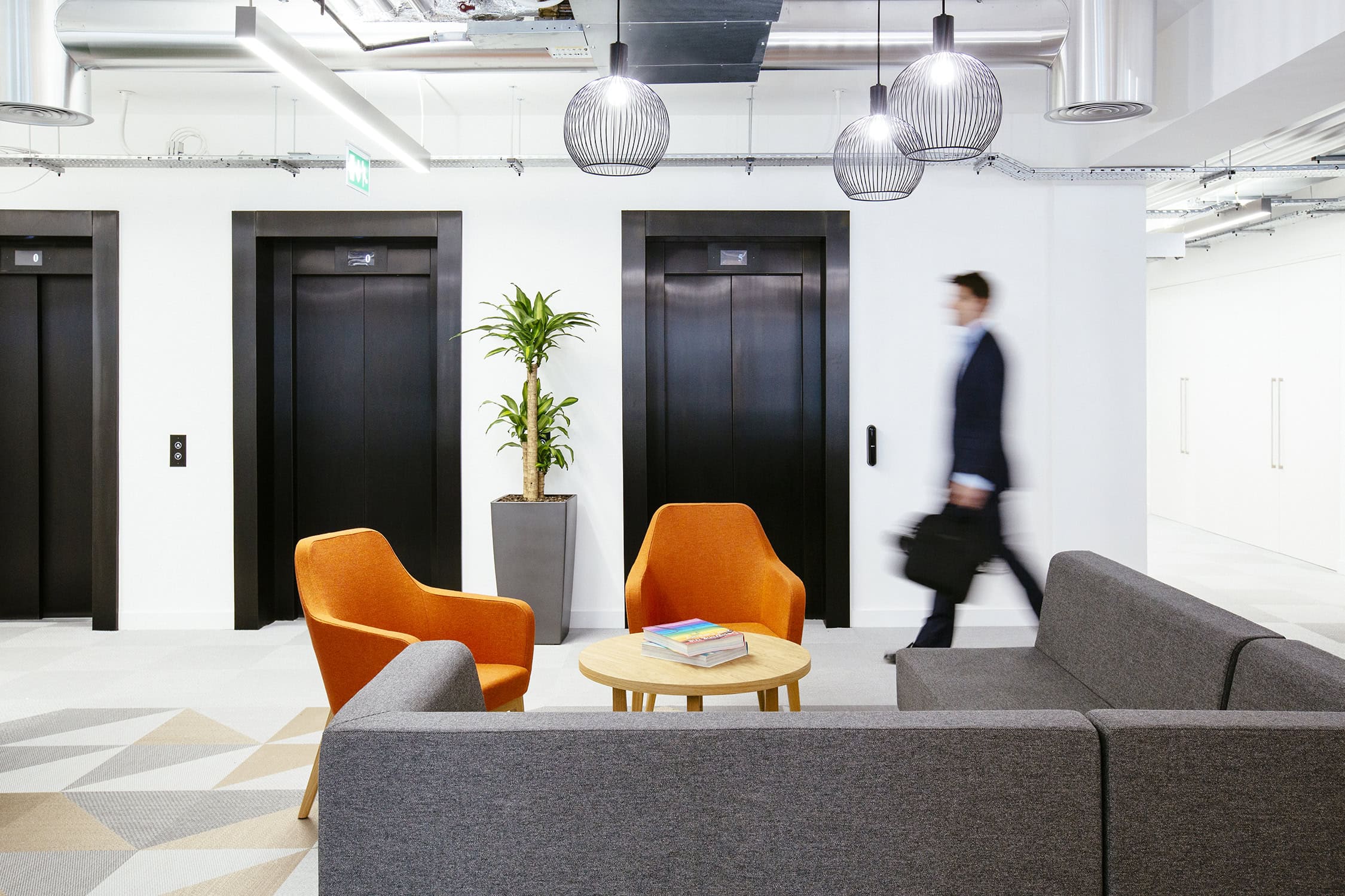 A man is shown walking towards a lift inside the offices of Versus Arthritis designed by AIS.