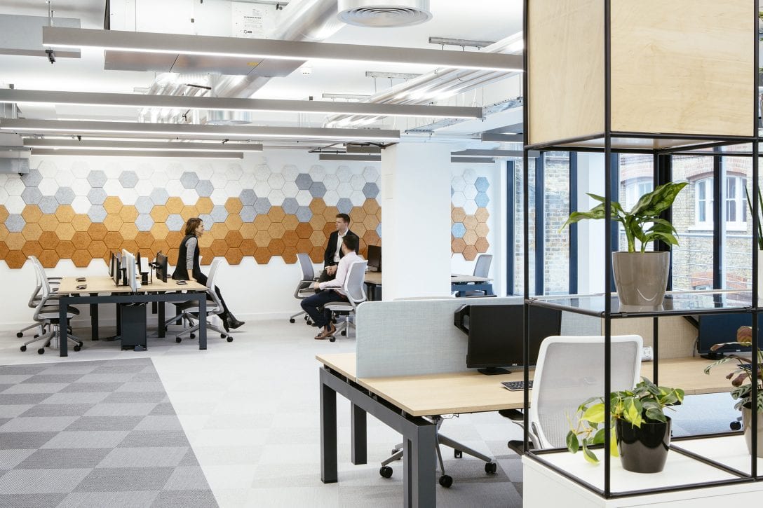 3 employees work inside an brightly lit office.