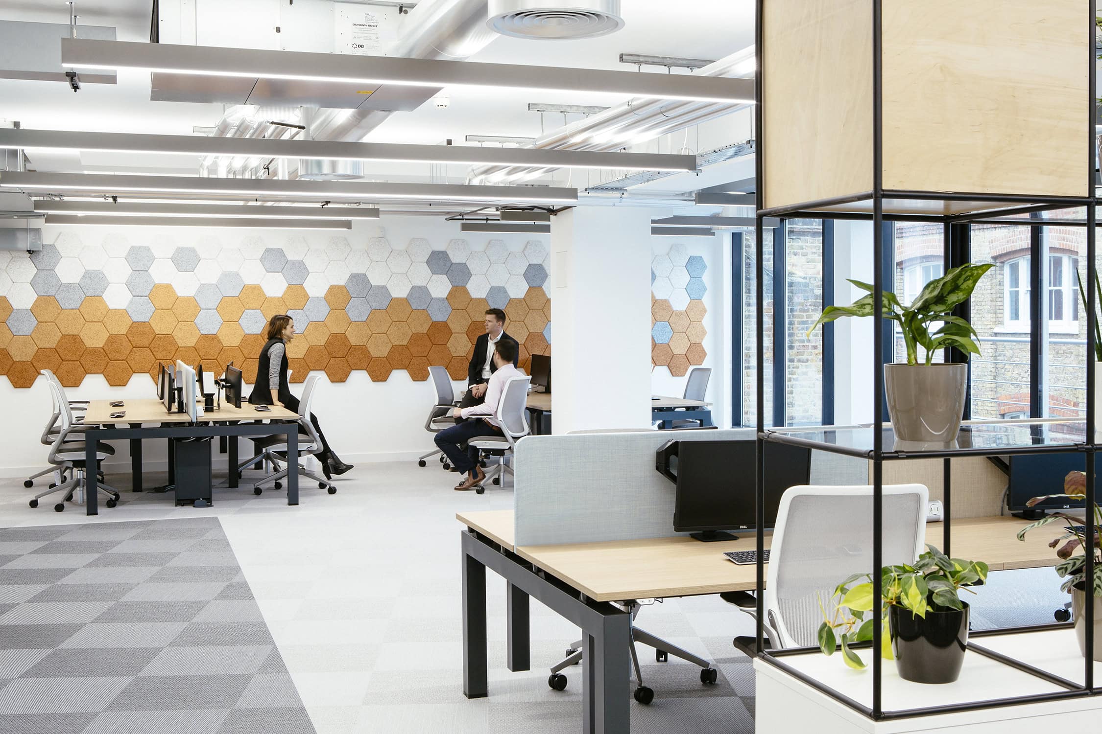 3 employees work inside an brightly lit office.