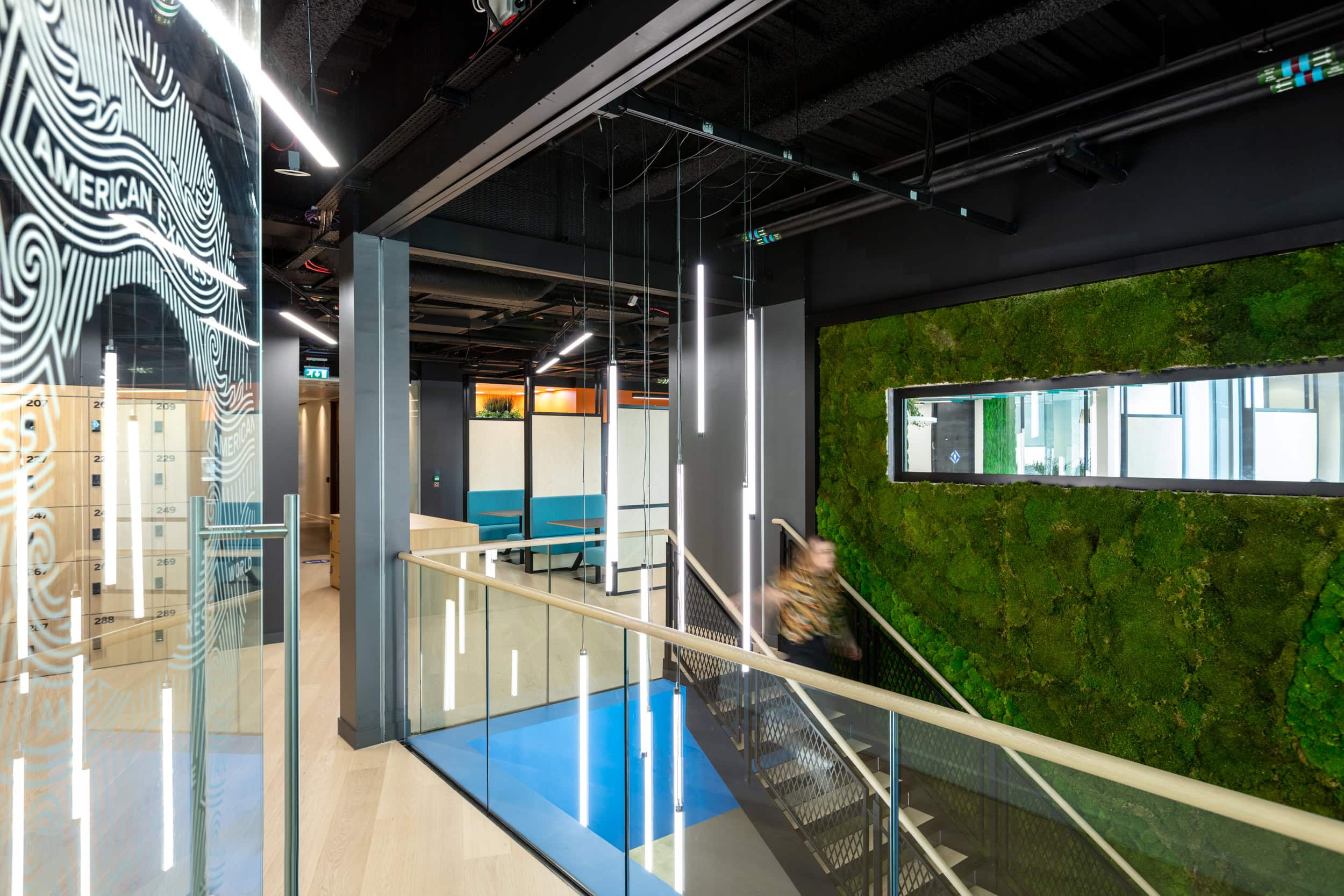 Image shows a woman walking down a staircase inside the hub office for a global corporate travel agent.