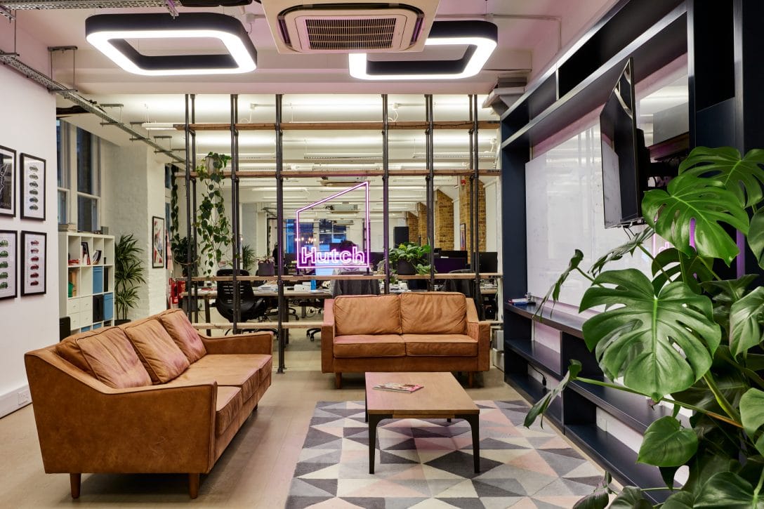 A break out area in the Hutch offices designed by AIS featuring a neon light with the Hutch company brand logo,