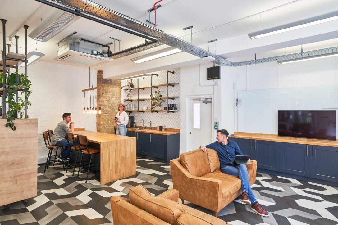 Employees are shown hanging out in the staff kitchen within an office designed by AIS to elevate employee experience.