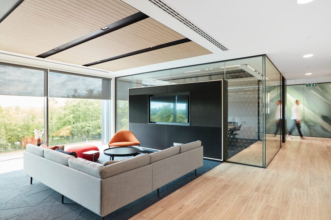A meeting room with a sofa and wall mounted tv inside a sustainable office design.
