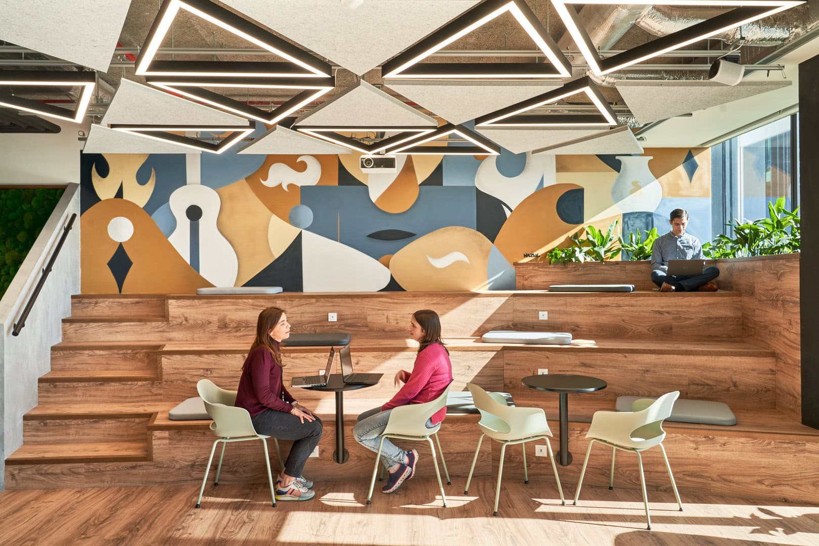 Employees are shown working on tiered bleacher seating inside an office designed for optimal activity based working.