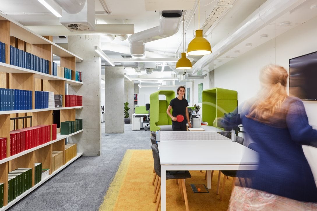 Two women playing table tennis in an AIS designed office.
