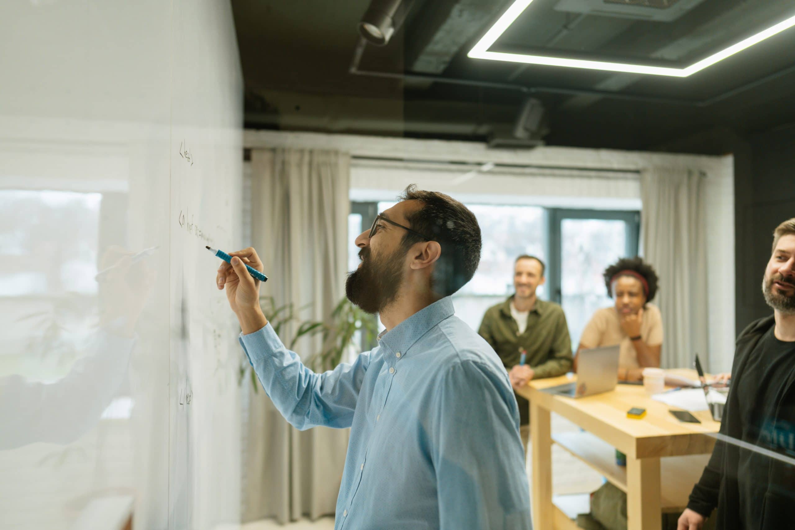 Photo of an AIS office designer leading a collaborative meeting with a whiteboard presentation