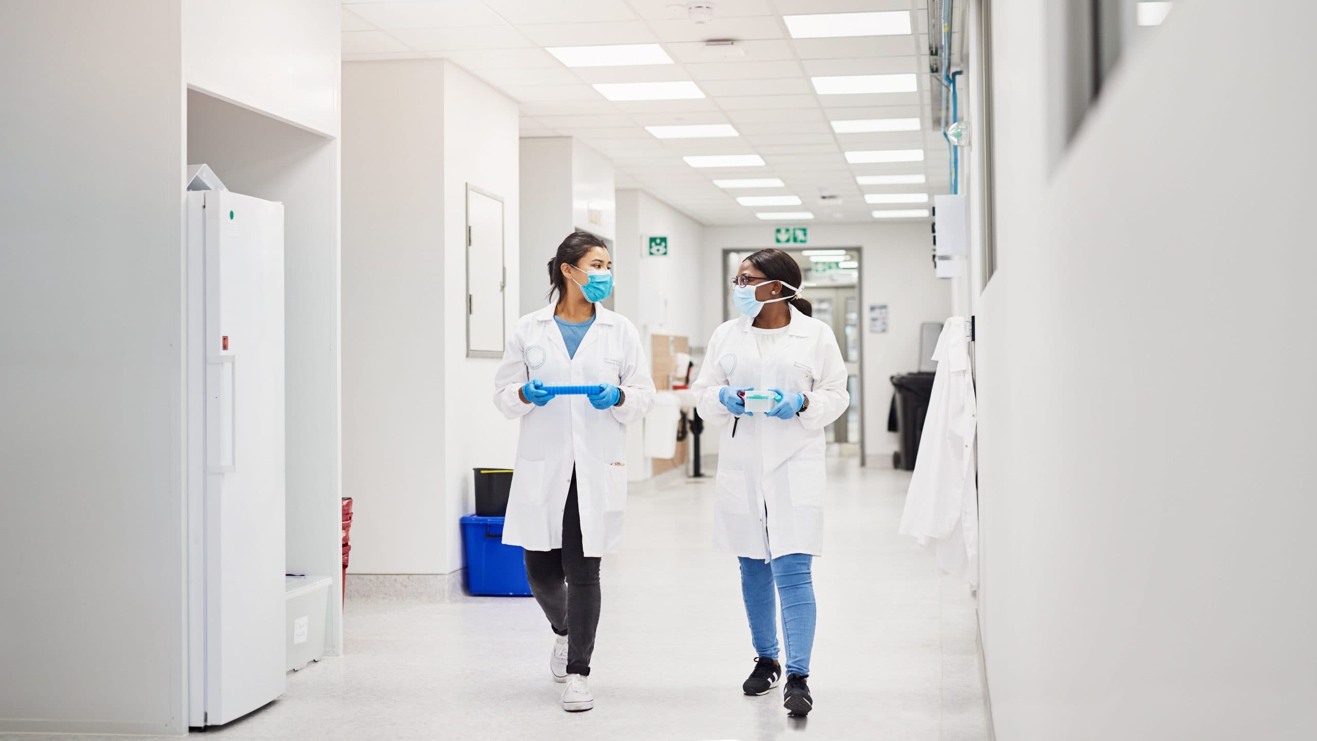 Two female scientists walking down the corridor of an AIS designed office-to-lab conversion.