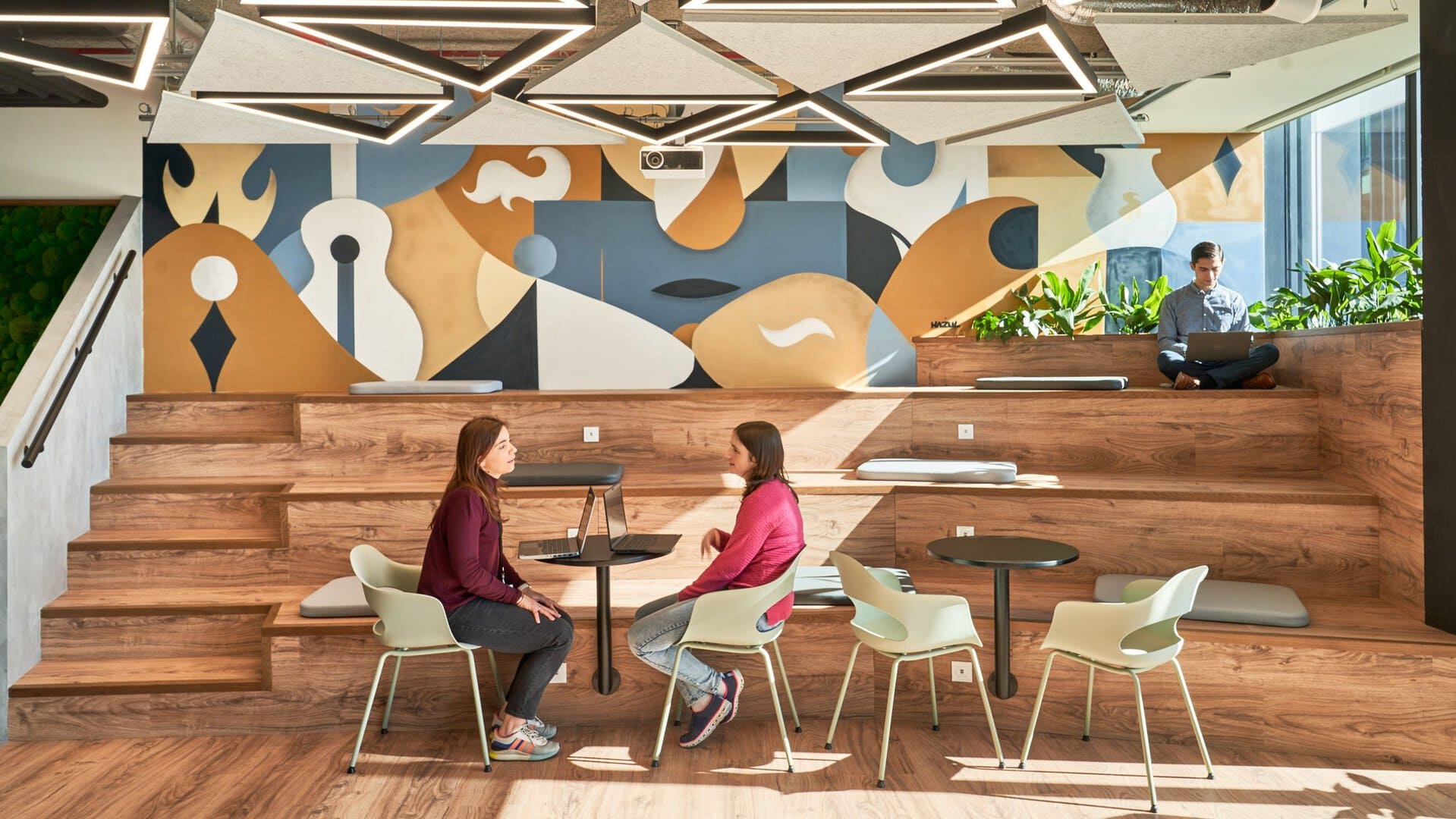 Employees are shown working on tiered bleacher seating inside an office designed for optimal activity based working.
