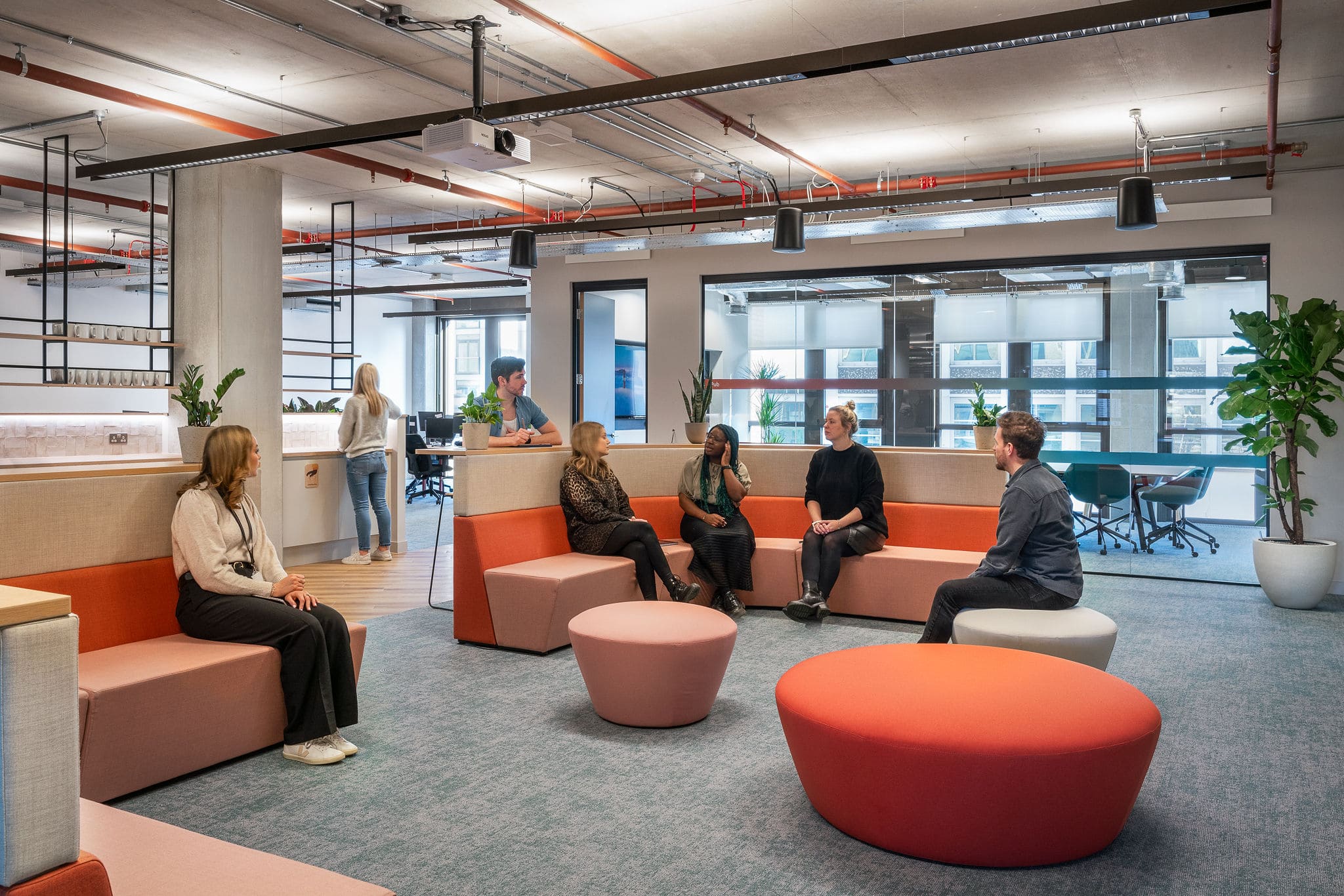 Large group of varied colleagues discussing across an open plan office area