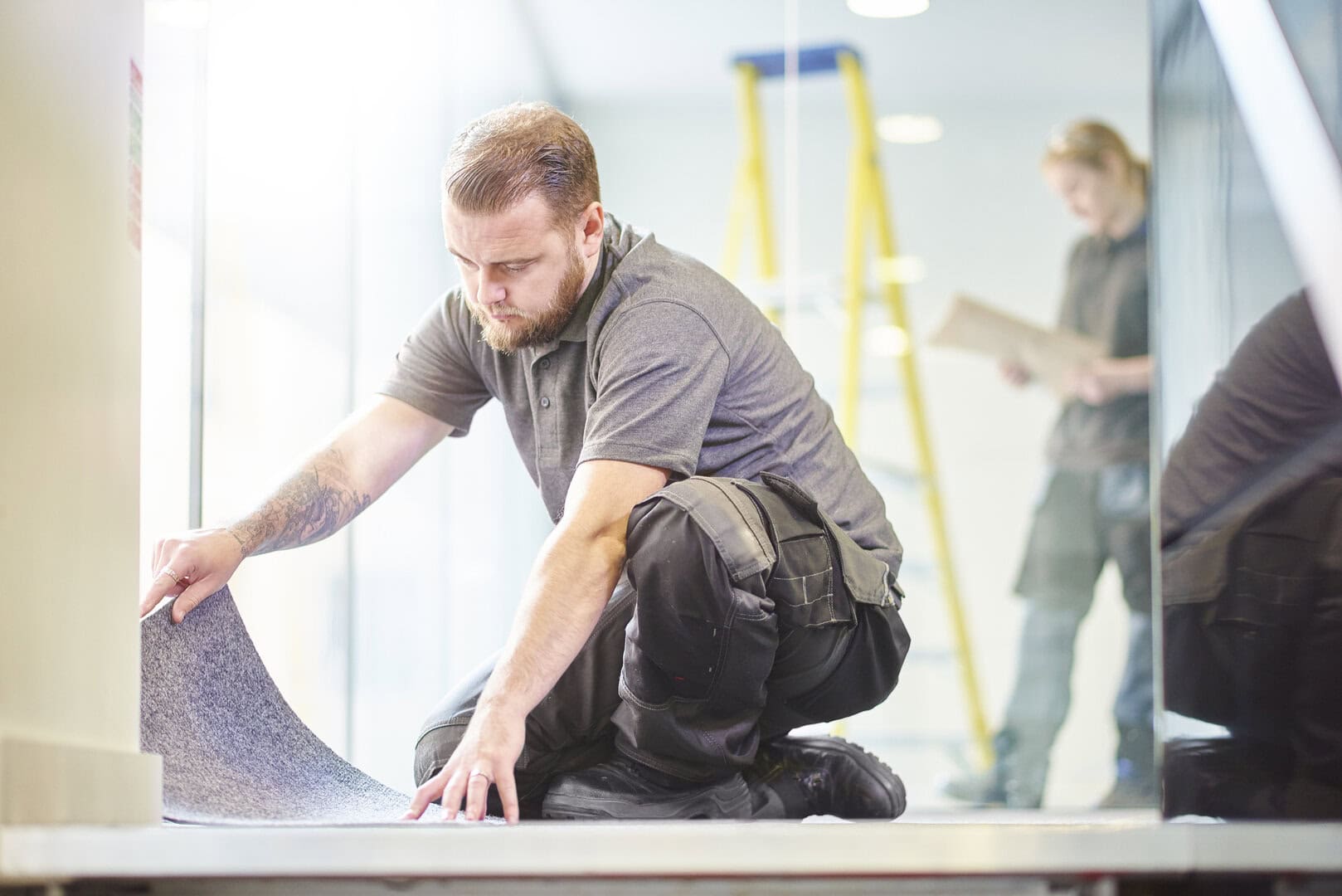 Construction worker laying down flooring on a live site